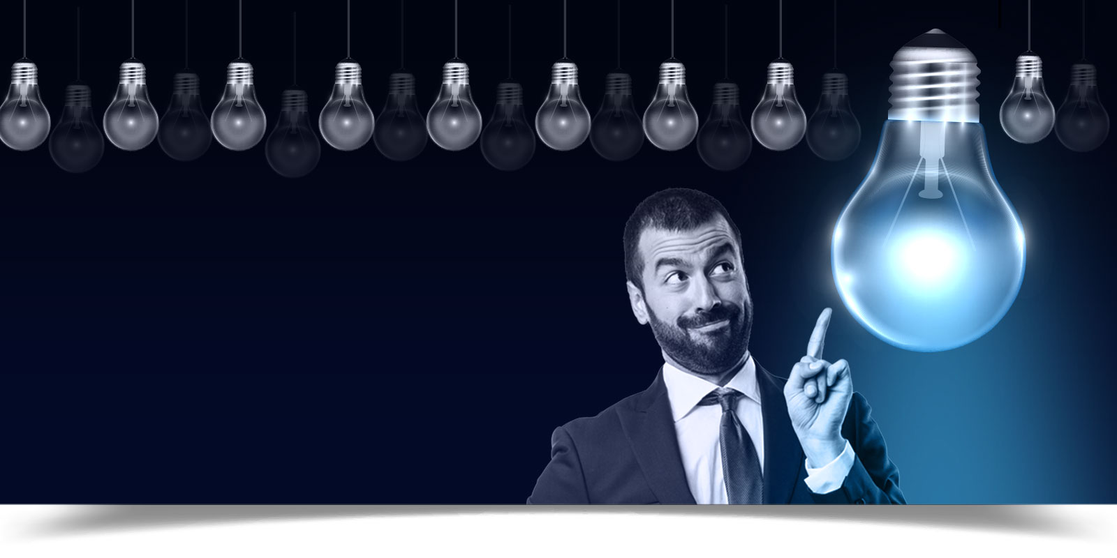 A businessman dressed in a suit with a lot of small bulbs above his head and one large bright one close to his face and he is pointing at it.